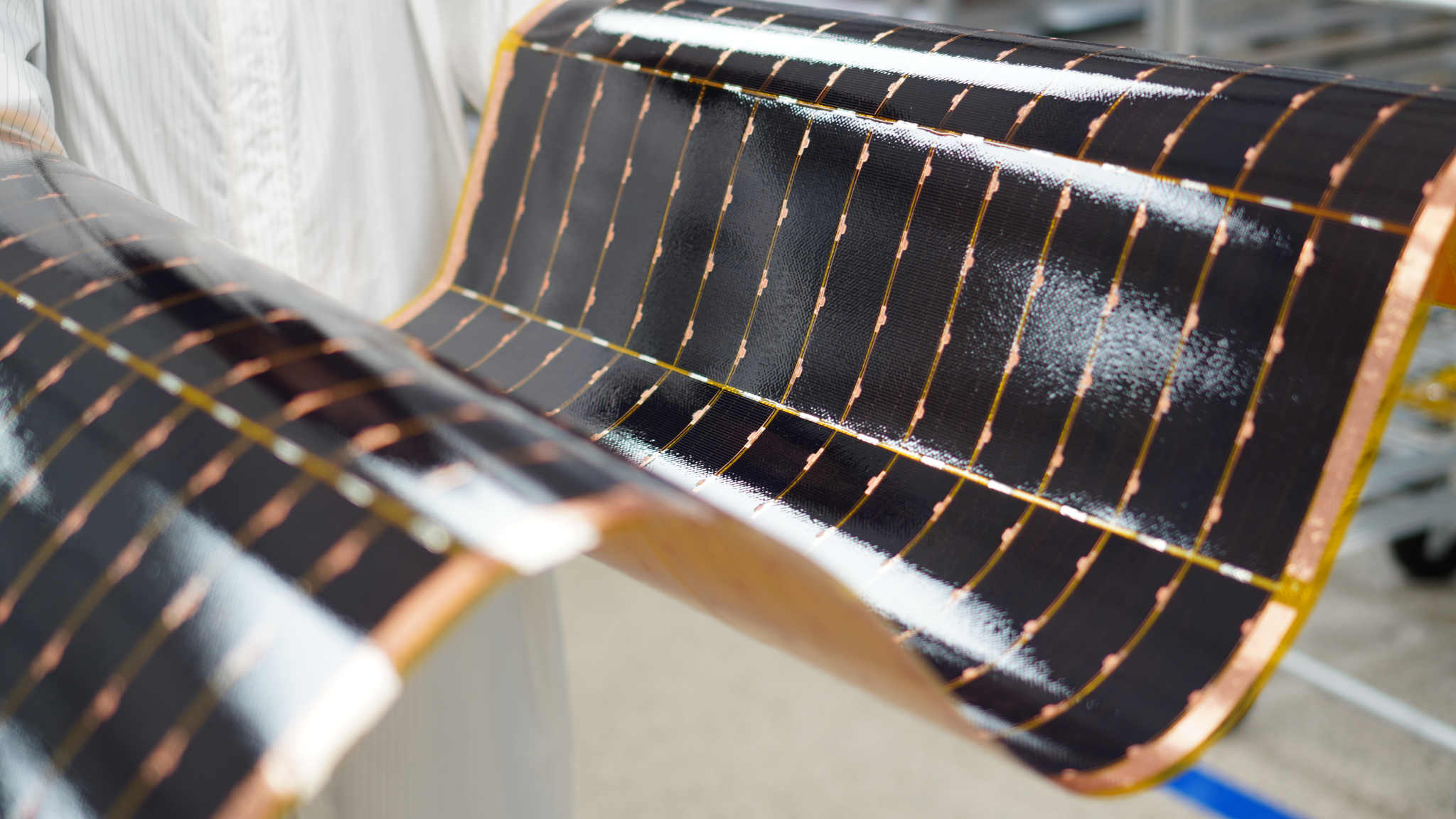 A technician holds a flexible solar power module manufactured by Solestial.
