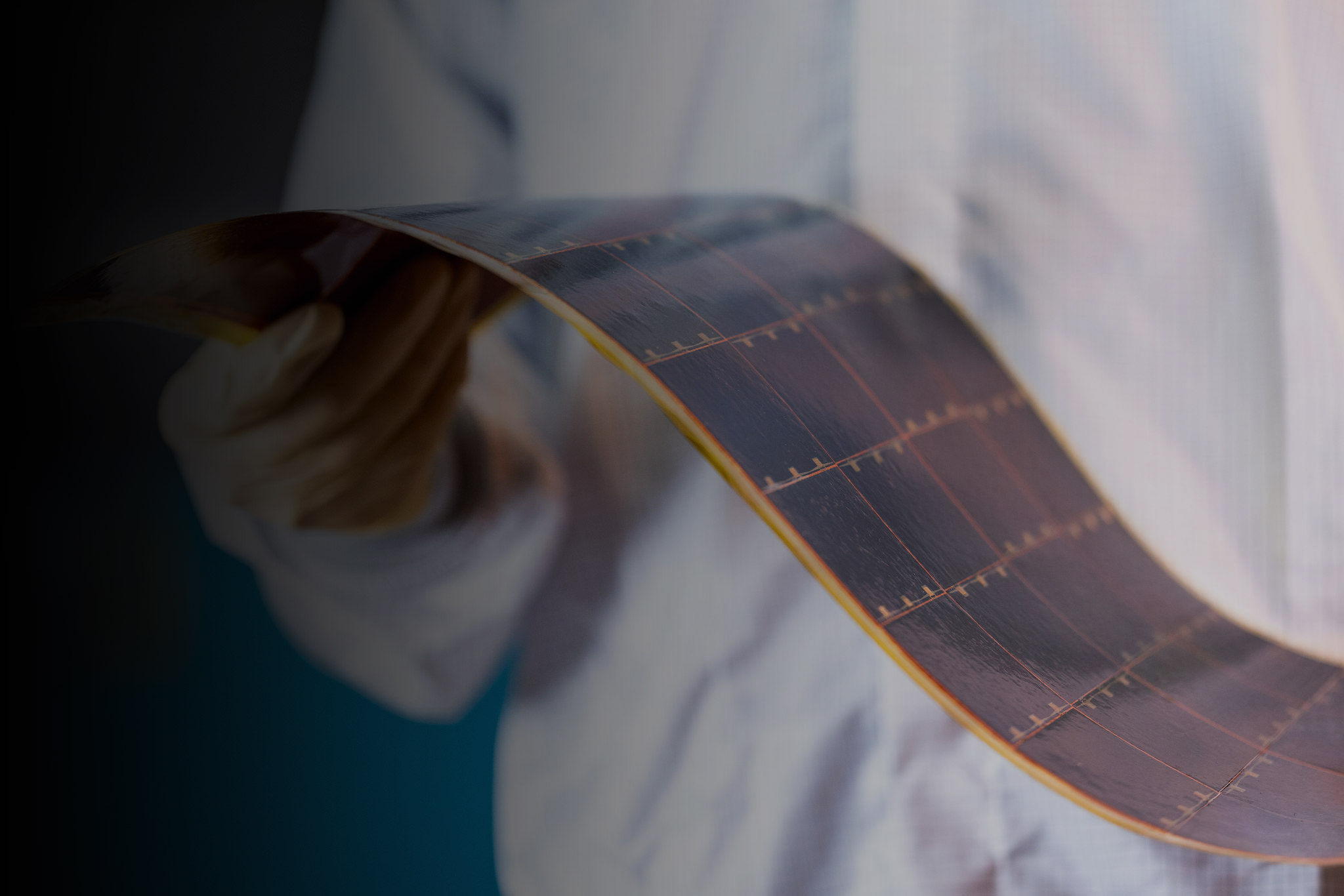 Side-angle view of a lab tech demonstrating the flexibility of a flexible solar power module, designed and manufactured by Solestial.