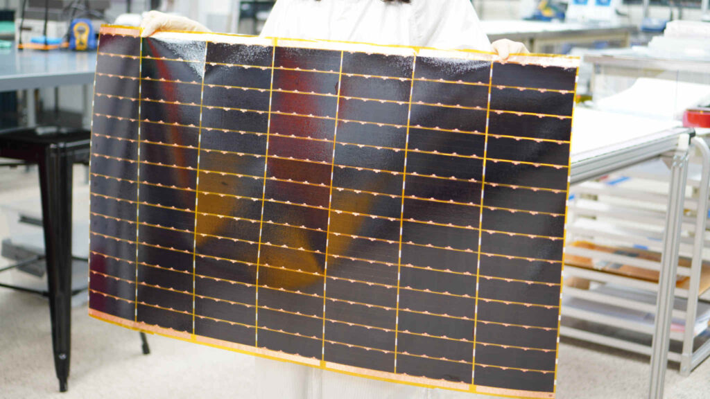 A technician holds a flexible solar power module, manufactured by Solestial